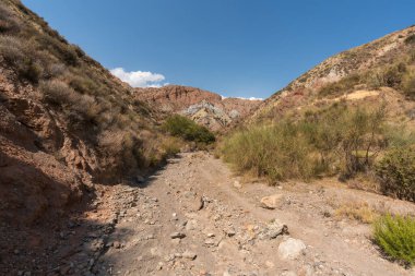 Güney İspanya 'da dağlık ve aşınmış bir arazi. Kuru bir vadi var, bitki örtüsü var ve gökyüzü bulutlu.