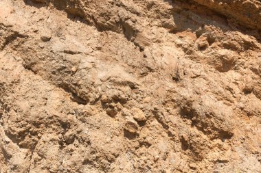 Bir dağda taş ve toprak yüzeyi, yüzeyi düz değildir, kahverengi renktedir.