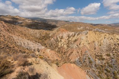 Güney İspanya 'da dağlık ve aşınmış bir arazi. Kuru bir vadi var, bitki örtüsü var ve gökyüzü bulutlu.