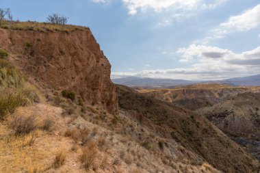 Güney İspanya 'da dağlık ve aşınmış bir arazi. Kuru bir vadi var, bitki örtüsü var ve gökyüzü bulutlu.