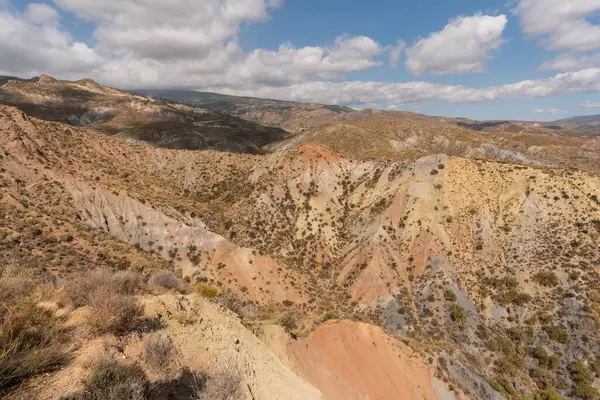 Güney İspanya 'da dağlık ve aşınmış bir arazi. Kuru bir vadi var, bitki örtüsü var ve gökyüzü bulutlu.