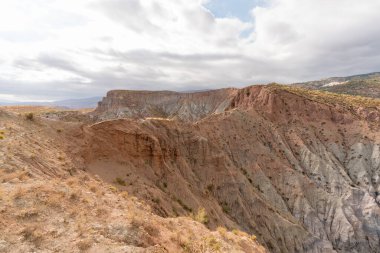 Güney İspanya 'da dağlık ve aşınmış bir arazi. Kuru bir vadi var, bitki örtüsü var ve gökyüzü bulutlu.