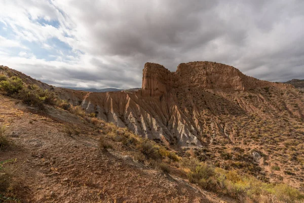 Güney İspanya 'da dağlık ve aşınmış bir arazi. Kuru bir vadi var, bitki örtüsü var ve gökyüzü bulutlu.