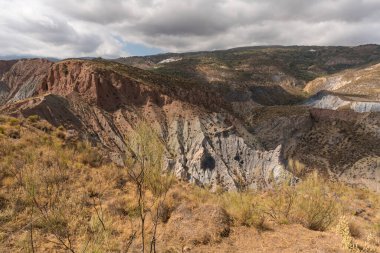 Güney İspanya 'da dağlık bir arazi, dağda bir köy var, çalılar var ve gökyüzünde bulutlar var.