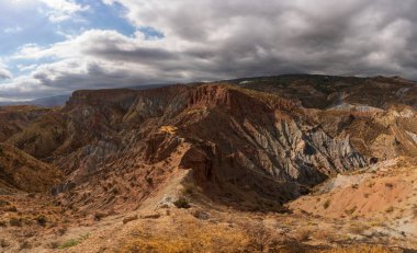 Güney İspanya 'da dağlık bir arazi, dağda bir köy var, çalılar var ve gökyüzünde bulutlar var.