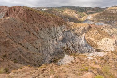 Güney İspanya 'da dağlık bir arazi, dağda bir köy var, çalılar var ve gökyüzünde bulutlar var.