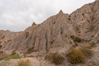 İspanya 'nın güneyindeki dağlık bölgede çalılar var, toprak aşınmış, gökyüzü bulutlu.