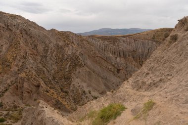 İspanya 'nın güneyindeki dağlık bölgede çalılar var, toprak aşınmış, gökyüzü bulutlu.