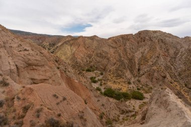 İspanya 'nın güneyindeki dağlık bölgede çalılar var, toprak aşınmış, gökyüzü bulutlu.