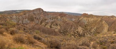 İspanya 'nın güneyindeki dağlık bölgede çalılar var, toprak aşınmış, gökyüzü bulutlu.