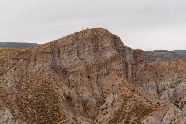 İspanya 'nın güneyindeki dağlık bölgede çalılar var, toprak aşınmış, gökyüzü bulutlu.