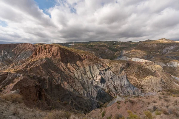 Güney İspanya 'da dağlık bir arazi, dağda bir köy var, çalılar var ve gökyüzünde bulutlar var.