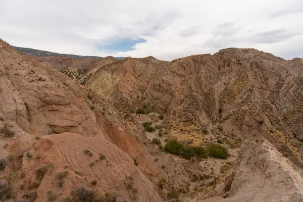 İspanya 'nın güneyindeki dağlık bölgede çalılar var, toprak aşınmış, gökyüzü bulutlu.