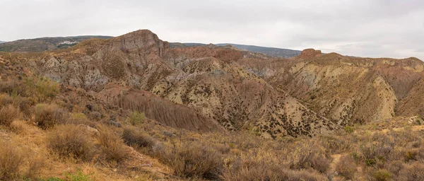 İspanya 'nın güneyindeki dağlık bölgede çalılar var, toprak aşınmış, gökyüzü bulutlu.