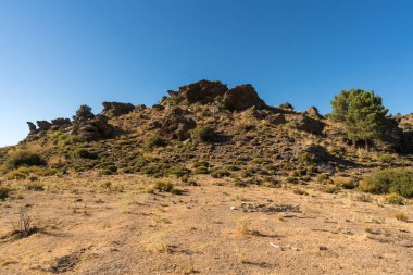 İspanya 'nın güneyindeki Sierra Nevada' da kaya oluşumu. Ağaçlar ve çalılar var, gökyüzü açık.