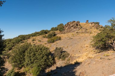 Güney İspanya 'da Sierra Nevada' da dağlar kadar arazi var. Çam ormanları ve çalılar var. Gökyüzünde bulutlar var.