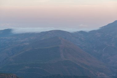 Güney İspanya 'da Sierra Nevada' da günbatımı, çam ormanları ve çalılar var, gökyüzünde bulutlar var.