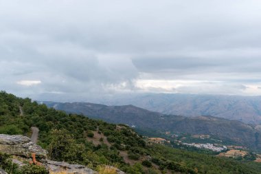 Güney İspanya 'da Sierra Nevada' da dağlar kadar arazi var. Ağaçlardan ve çalılardan oluşan ormanlar var. Dağ yamacında bir köy var.
