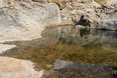 Sierra Nevada 'da bir vadiden aşağı akan su, kayalar ve taşlar, çalılar ve çimenler var.