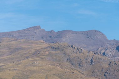 Sierra Nevada 'nın dağlık arazisi, çimenler ve çalılar var, taşlar ve kayalar var, gökyüzü açık.