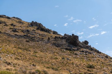 Sierra Nevada 'nın dağlık arazisi, çimenler ve çalılar, taşlar ve kayalar var, gökyüzünde bulut var.