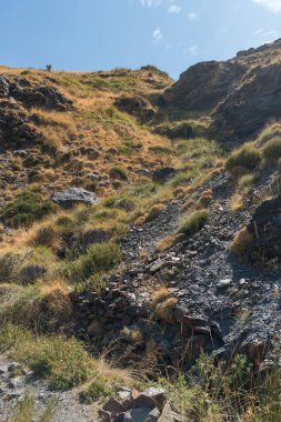 Sierra Nevada 'nın dağlık arazisi, çimenler ve çalılar var, taşlar ve kayalar var, gökyüzü açık.