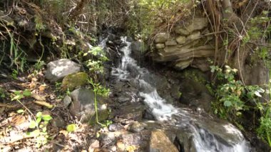 stream of water on the mountain, there are stones and rocks, there is grass