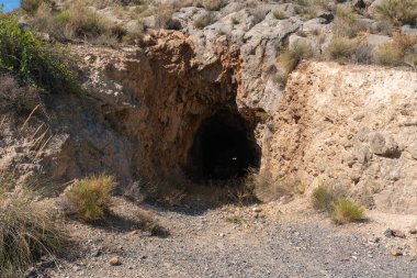 Güney İspanya 'da eski bir maden galerisi, galeri bir kayanın içinde kazılmış, çalılar ve taşlar var.
