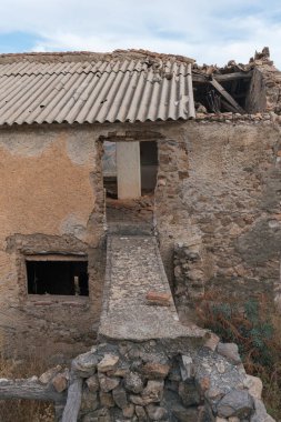 Güney İspanya 'daki harabe çiftlik evi, taştan yapılmış çiftlik evi, birkaç pencere ve bir kapı, gökyüzünde bulutlar var.