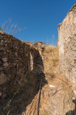 Güney İspanya 'daki harap çiftlik evi, taştan yapılmış çiftlik evi, bir kaç pencere ve bir kapı, dağlar, çalılar ve kuru çimenler var, gökyüzü temiz.