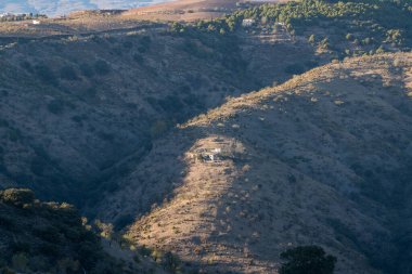 Güney İspanya 'nın dağlık arazisi, ağaçlar ve çalılar var, bir çiftlik evi var, geçitleri olan bir alan.