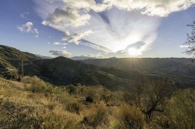 İspanya 'nın güneyindeki dağlık bölgede, dağlarda ağaçlar ve çalılar var, gökyüzünde bulutlar var.