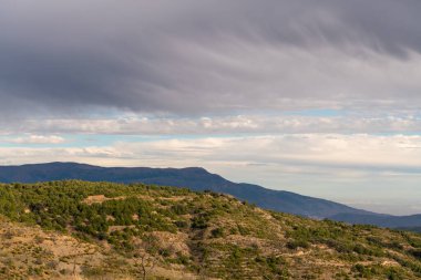 Güney İspanya 'nın dağlık arazisi, dağlarda ağaçlar, gökyüzünde bulutlar var.