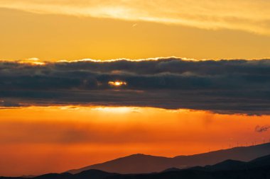 Güney İspanya 'nın dağlık arazisi, günbatımı ve güneş bulutların arasında saklı.