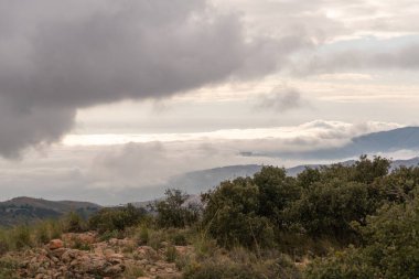 Güney İspanya 'da dağlar, dağlarda ağaçlar, bulutlar dağları kaplıyor.