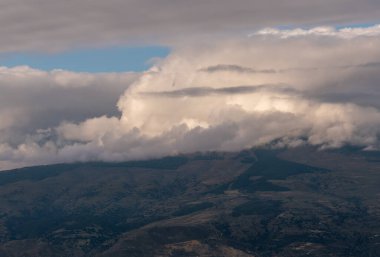 Güney İspanya 'nın dağlık arazisi, dağlarda ağaçlar ve çalılar var, gökyüzünde bulutlar var.