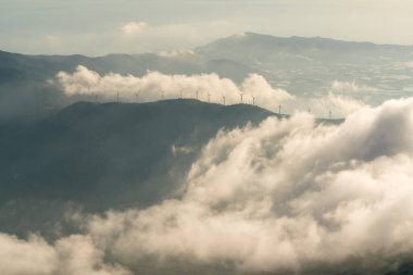 Güney İspanya 'daki bulutların arasında dağlar, rüzgar türbinleri, telekomünikasyon antenleri, ağaçlar ve arka planda Akdeniz var..