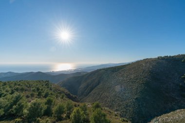 Güney İspanya 'nın dağlık arazisi, dağ çalılarla ve ağaçlarla kaplıdır, arka planda Akdeniz vardır.