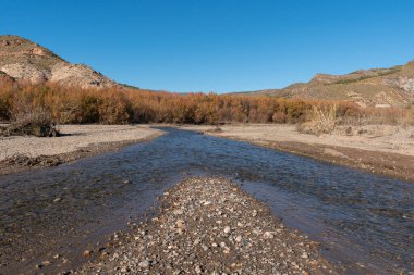 İspanya 'nın güneyinde su olan nehir, dağlar, ağaçlar ve çalılar, taşlar ve kum var, gökyüzü temiz.