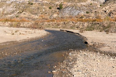 İspanya 'nın güneyinde su olan nehir, dağlar, ağaçlar ve çalılar, taşlar ve kum var.