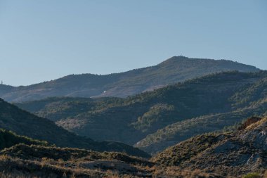 Güney İspanya 'nın dağlık arazisi, ağaçlar ve çalılar, kayalar ve taşlar var, gökyüzü açık.