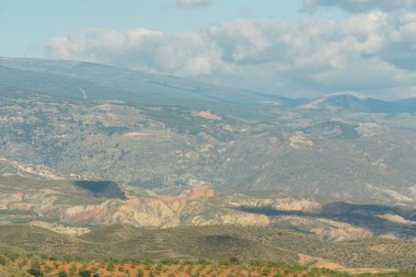 Güney İspanya 'nın dağlık arazisi, birkaç badem ve zeytin ağacı ekini, vadiler, gökyüzü bulutlu.