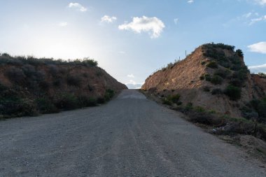 Güney İspanya 'da toprak yol, çalılar var ve gökyüzünde bulutlar var.