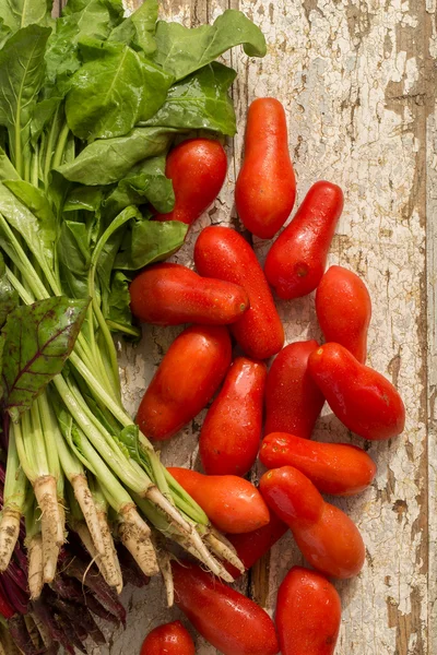 Hojas de remolacha y tomates sobre el viejo fondo de madera — Foto de Stock