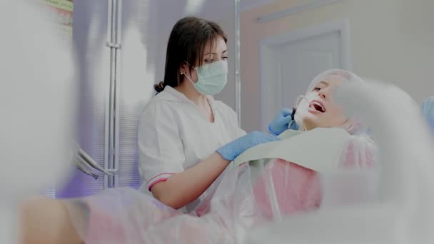 Девушка пьет воду в стоматологии во время лечения — стоковое видео