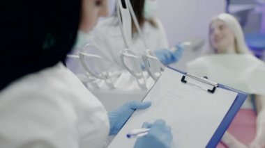 Doktor dişçi ofisinde bir hastada incelerken Yardımcısı notlar alır