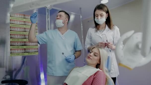 Due medici esaminano una bella ragazza su una sedia nello studio dentistico — Video Stock