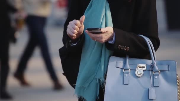 Vrouw staande met telefoon en blauwe handtas . — Stockvideo