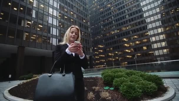 Framgångsrika Lady går omkring två skyskrapor med telefonen i handen. Chicago City Center — Stockvideo