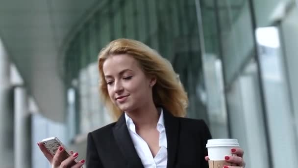Успішна і красива дівчина з телефоном і кавою в руці. дівчина в хмарочосі — стокове відео